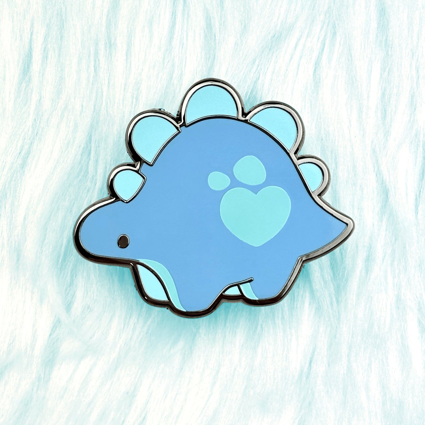 cute dinosaur enamel pin of a blue stegosaurus with a loveheart spot.