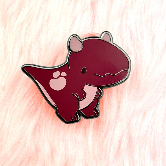 Cute dinosaur enamel pin of a carnotaurus with maroon colouring and a loveheart spot.