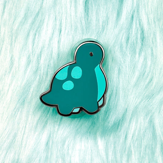 Cute baby dinosaur enamel pin of a diplodocus. It has a dark green color and cyan belly. 