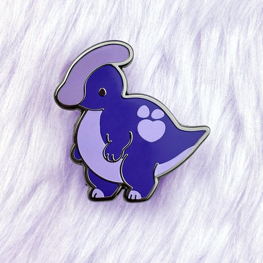 Cute dinosaur enamel pin of a purple parasauralophus with a loveheart spot.