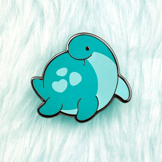 Cute dinosaur enamel pin of a plesiosaur with a loveheart spot and blue-green color.