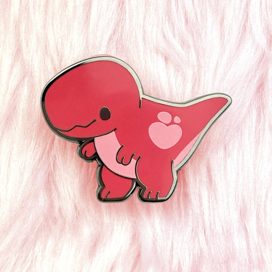 cute dinosaur pin of a red tyrannosaurus rex with pink details and a loveheart spot.