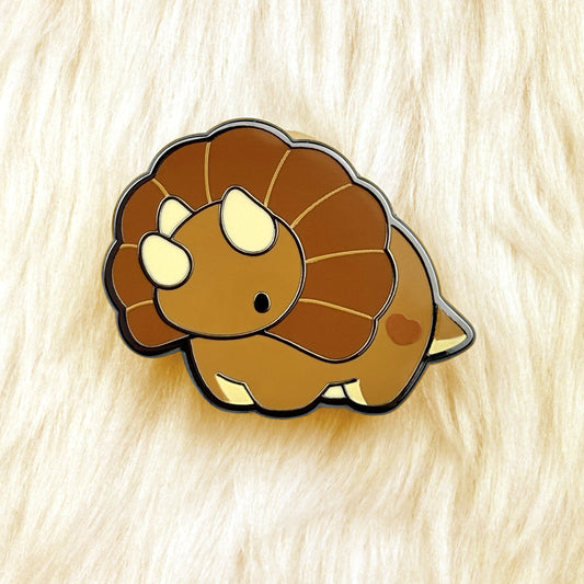 cute dinosaur enamel pin of a brown triceratops with black nickel plating. 